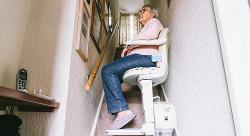 Image of a woman sat on a stair-lift in her home